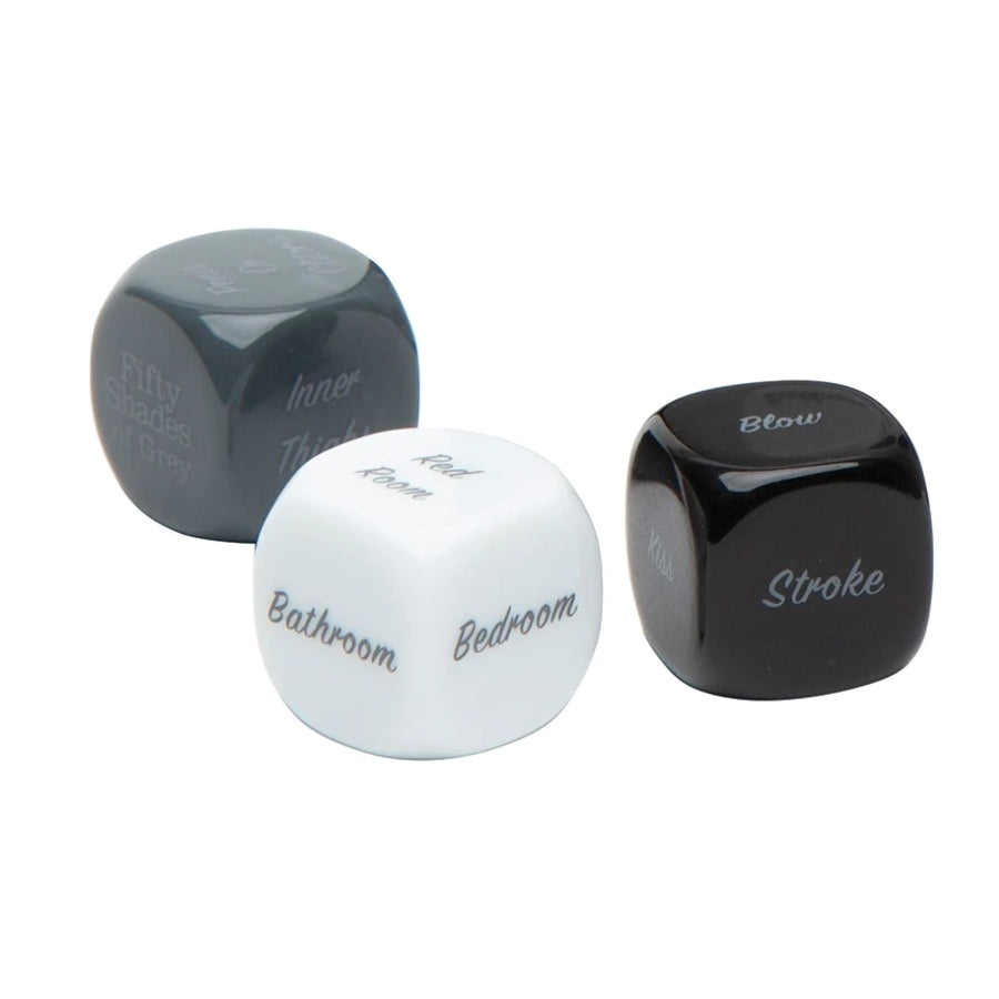 Fifty Shades of Grey Play Nice Role Play Dice set featuring three black dice with white text, each showing a category: action, body part, and location — designed to inspire romantic and playful scenarios.
